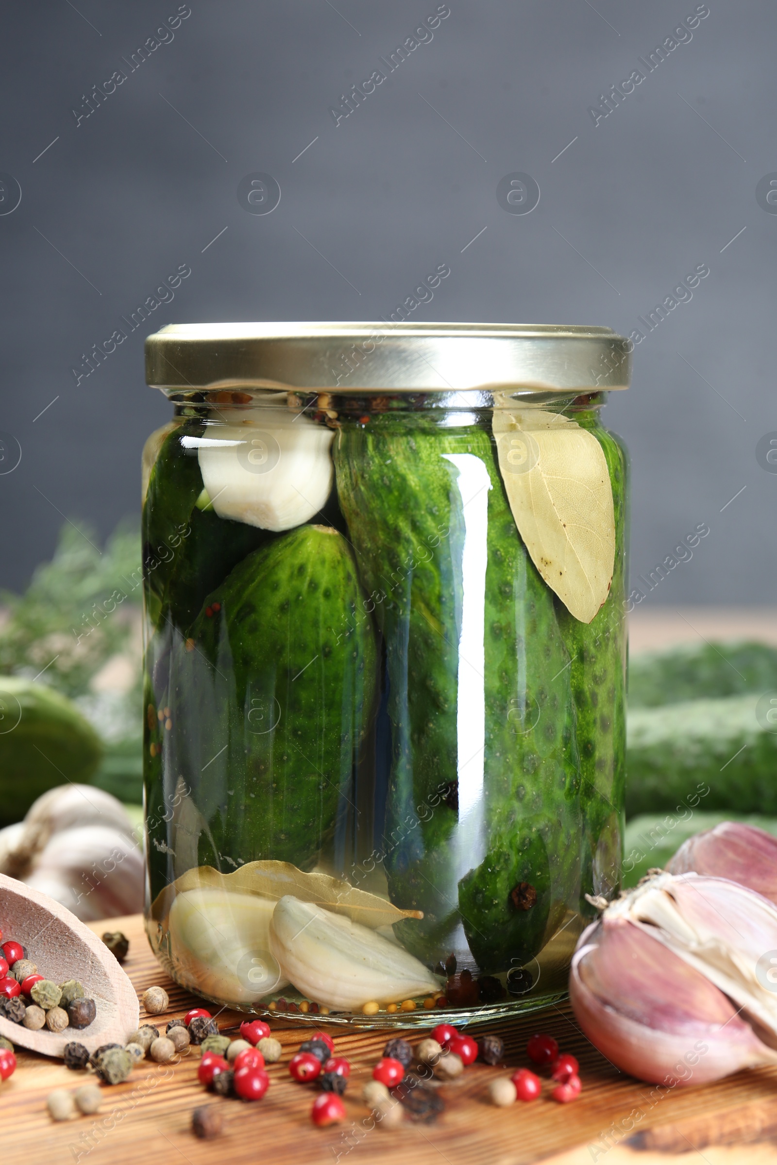 Photo of Making pickles. Fresh cucumbers and spices in jar on wooden table, closeup