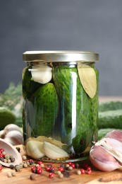 Photo of Making pickles. Fresh cucumbers and spices in jar on wooden table, closeup