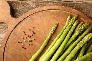 Photo of Board with fresh green asparagus stems and shakers on wooden table, flat lay