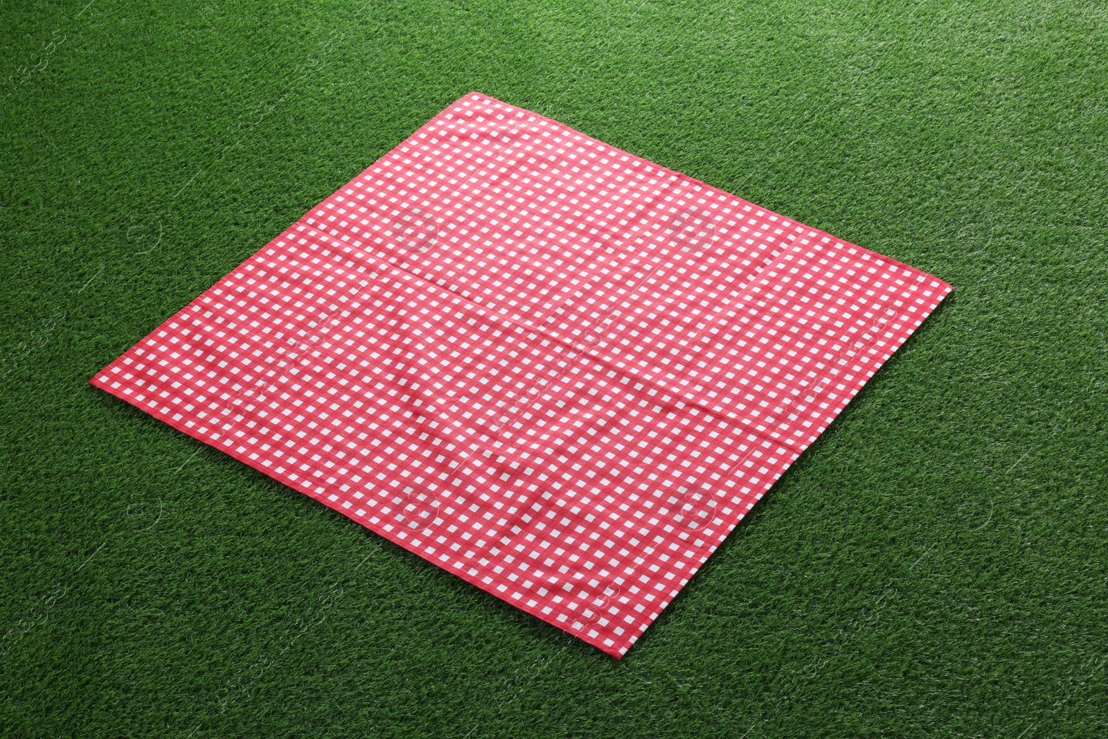 Photo of Red checkered picnic tablecloth on green grass