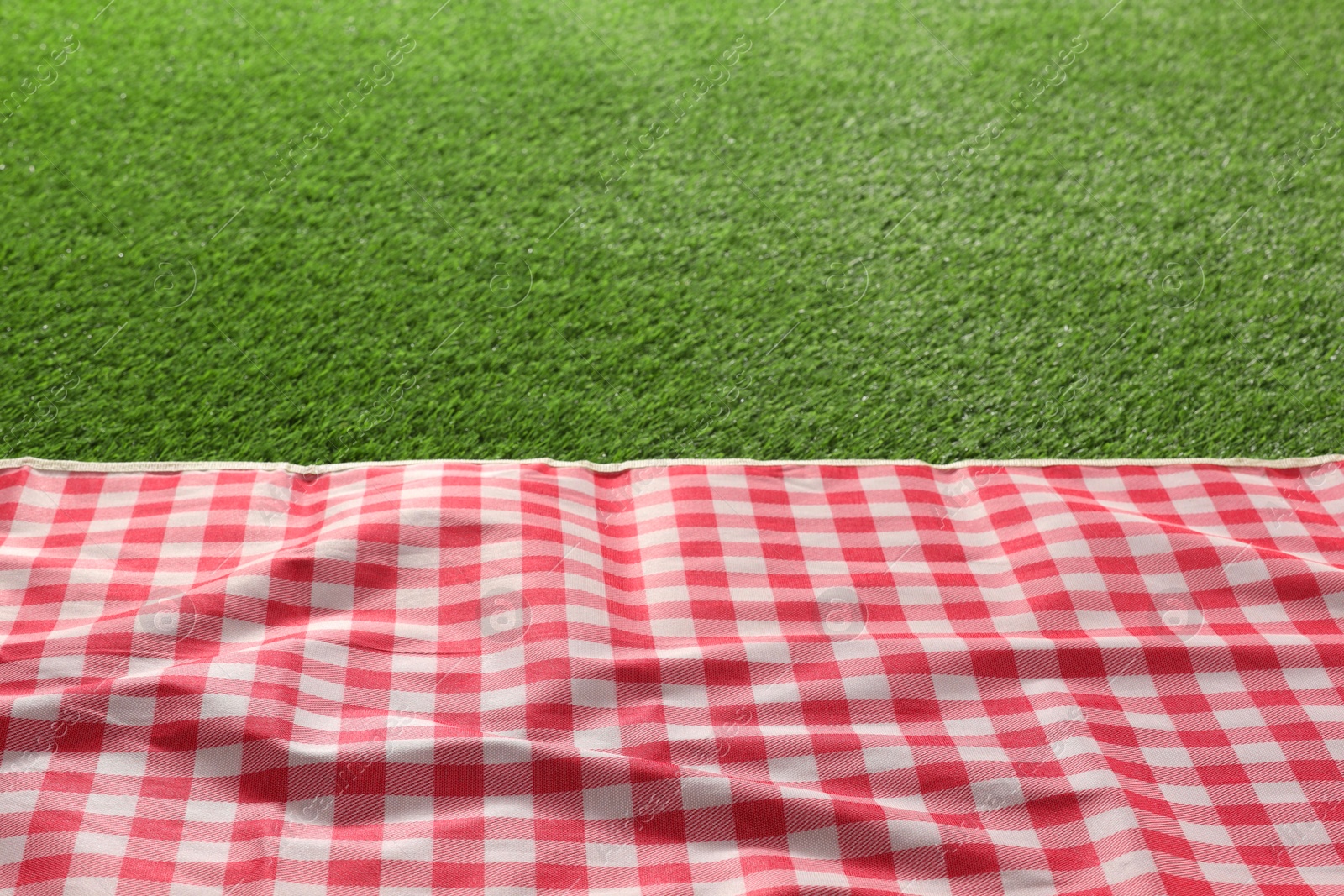 Checkered picnic tablecloth on green grass, closeup. Space for text Photo of Checkered picnic tablecloth on green grass, closeup. Space for text