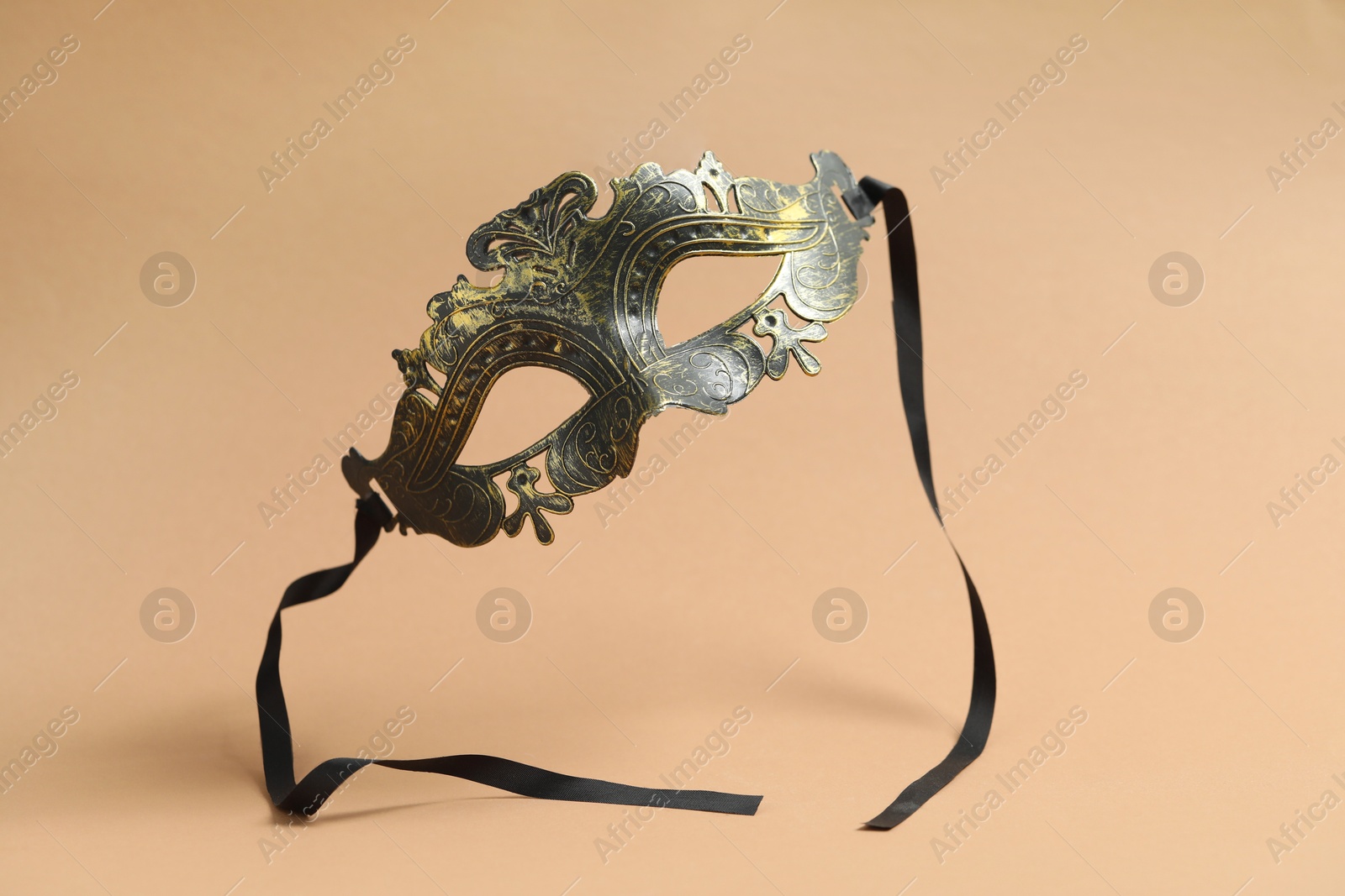 Photo of Beautiful carnival mask in air on beige background