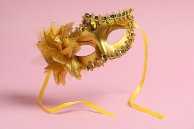 Photo of Beautiful carnival mask in air on pink background