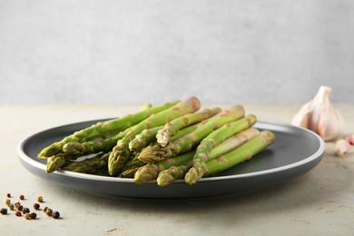 Photo of Fresh green asparagus stems on gray table, closeup