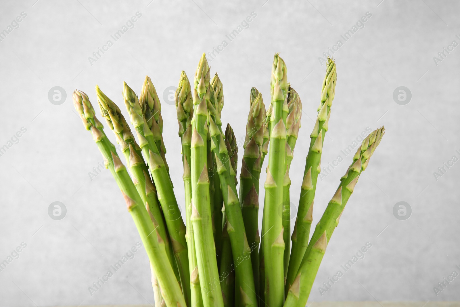 Photo of Fresh green asparagus stems on gray background, closeup