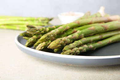 Photo of Fresh green asparagus stems on gray table, closeup