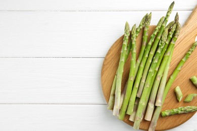 Photo of Fresh green asparagus stems on white wooden table, flat lay. Space for text