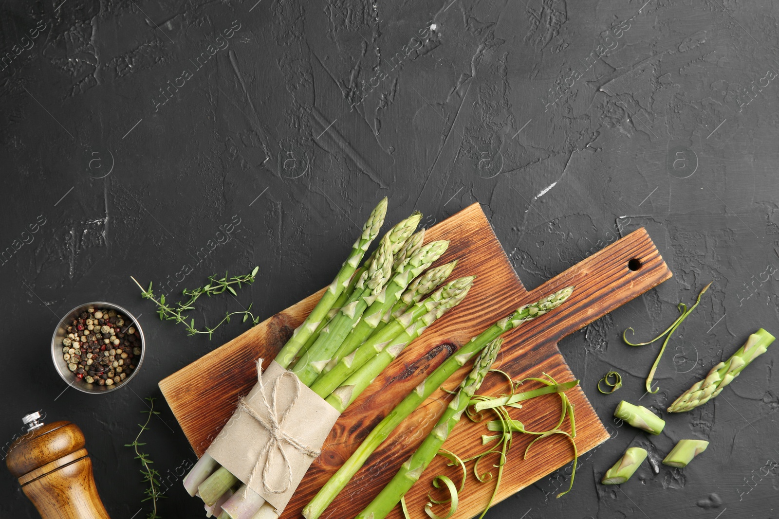 Photo of Fresh green asparagus stems and spices on gray textured table, flat lay. Space for text