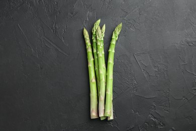 Photo of Fresh green asparagus stems on gray textured table, top view