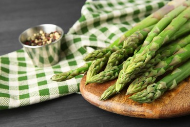 Photo of Fresh green asparagus stems and spices on gray wooden table, closeup