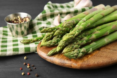 Photo of Fresh green asparagus stems and spices on gray wooden table, closeup