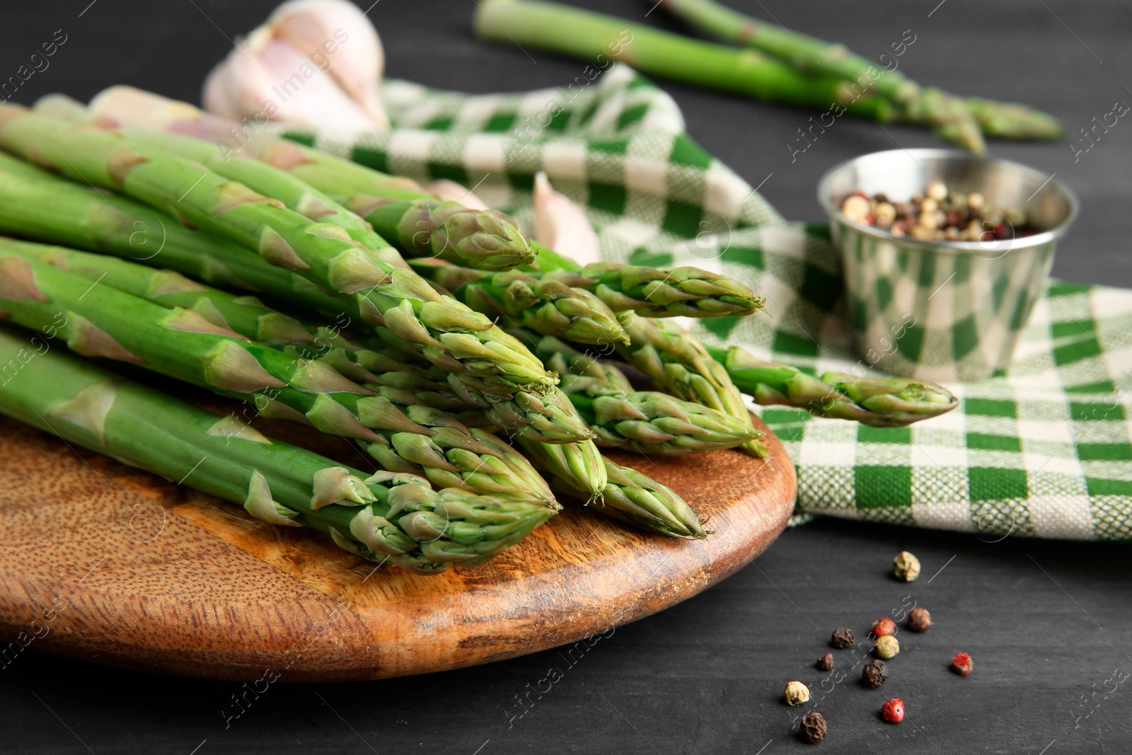 Photo of Fresh green asparagus stems and spices on gray wooden table, closeup