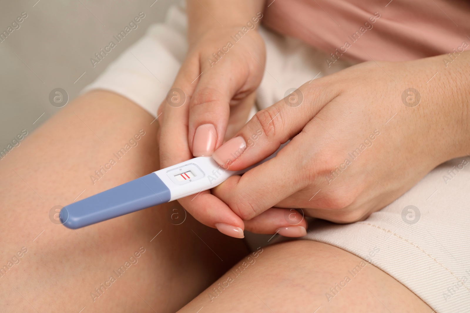 Photo of Woman holding negative pregnancy test indoors, closeup view