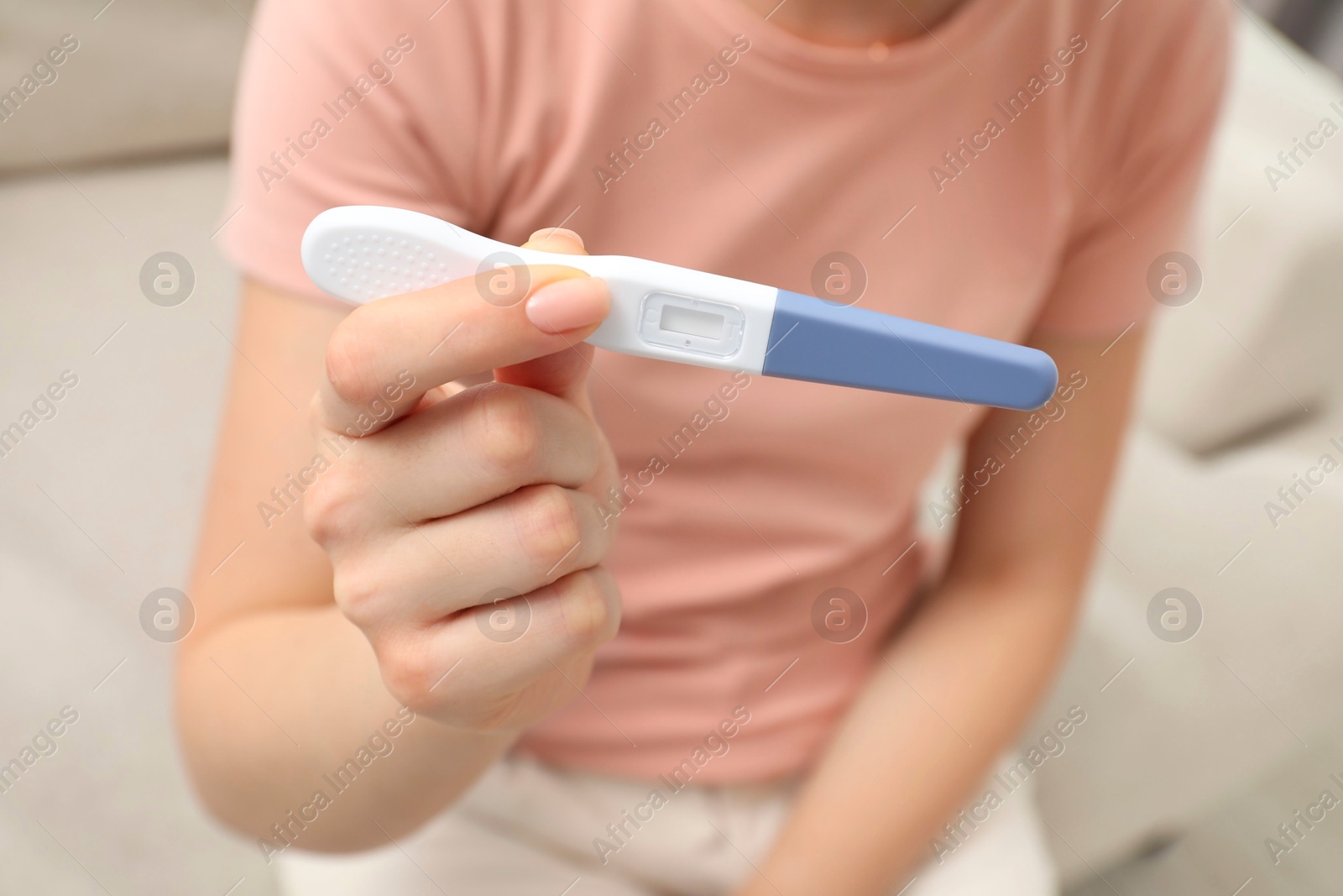 Photo of Woman holding pregnancy test indoors, closeup view