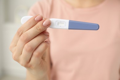 Photo of Woman holding pregnancy test indoors, closeup view