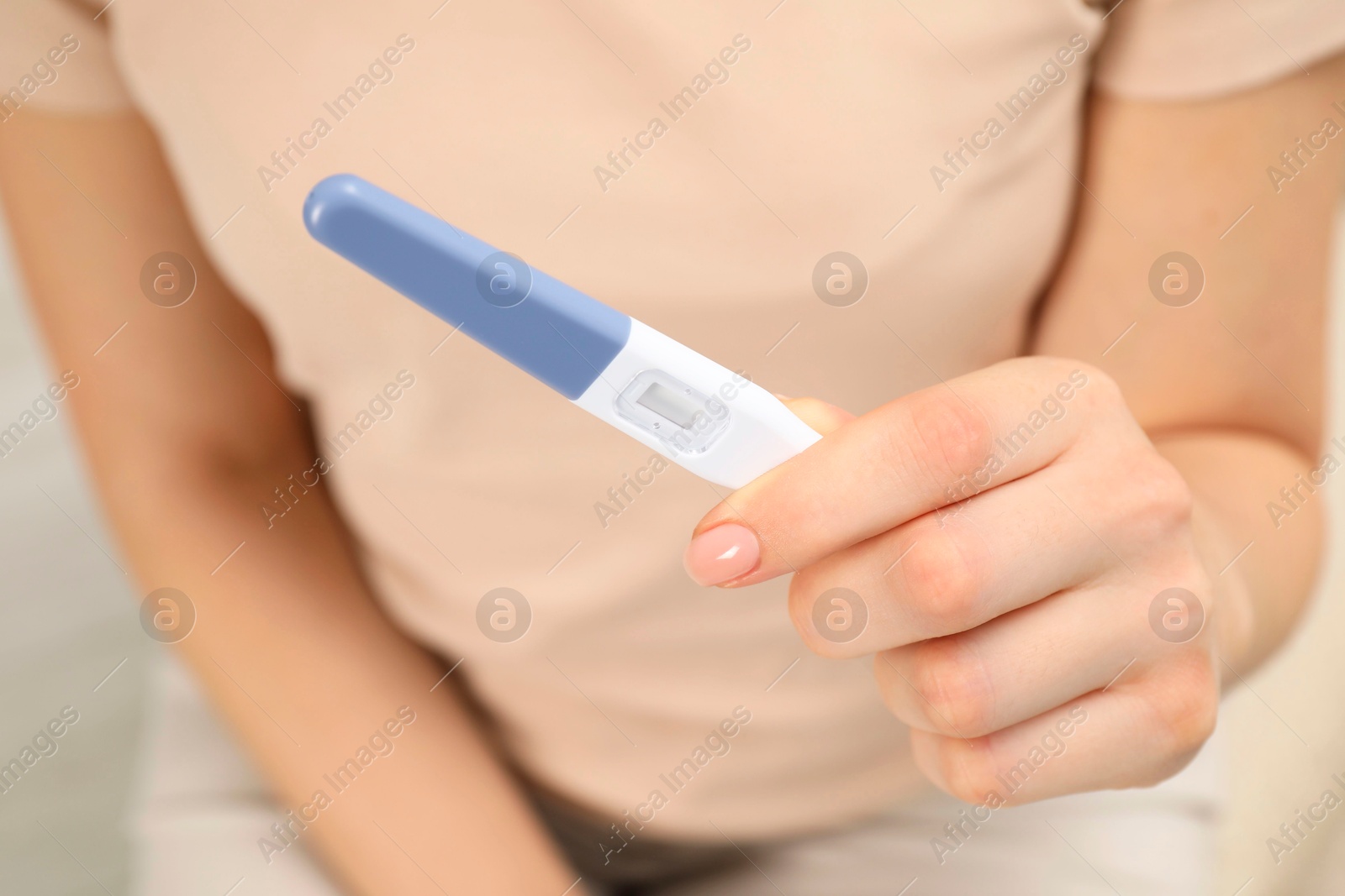 Photo of Woman holding pregnancy test indoors, closeup view