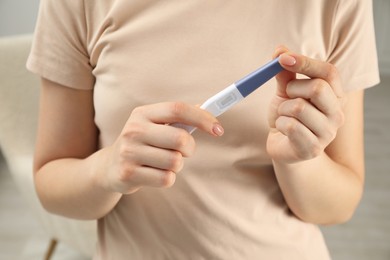 Photo of Woman holding pregnancy test indoors, closeup view