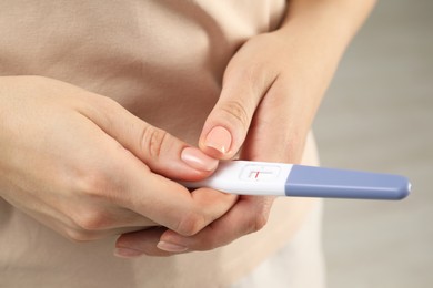 Photo of Woman holding negative pregnancy test indoors, closeup view