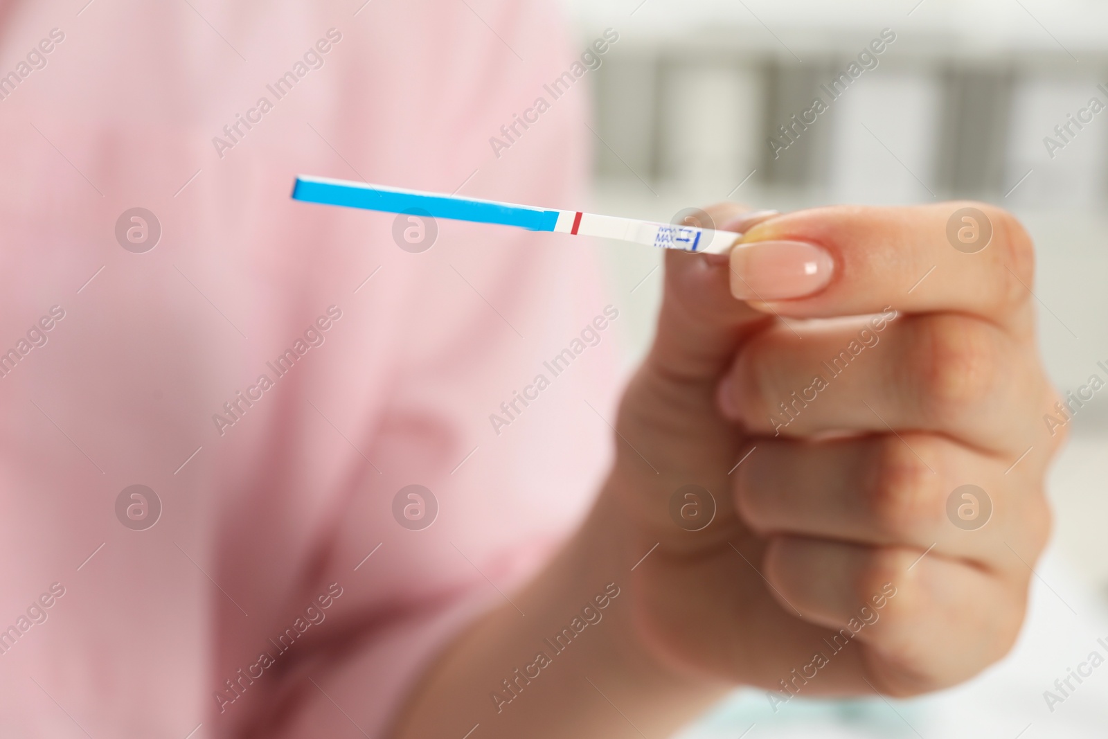 Photo of Woman holding negative pregnancy test indoors, closeup view