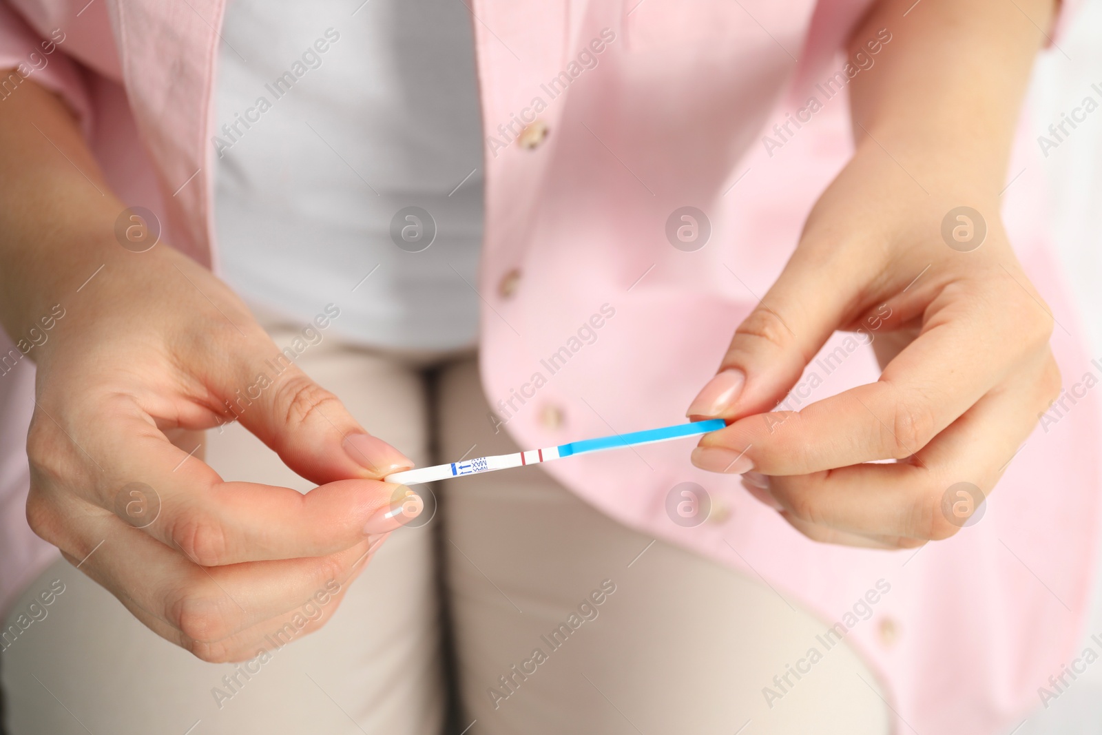 Photo of Woman holding positive pregnancy test indoors, closeup view