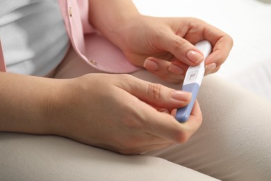 Photo of Woman holding pregnancy test indoors, closeup view