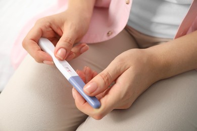 Woman holding negative pregnancy test indoors, closeup view