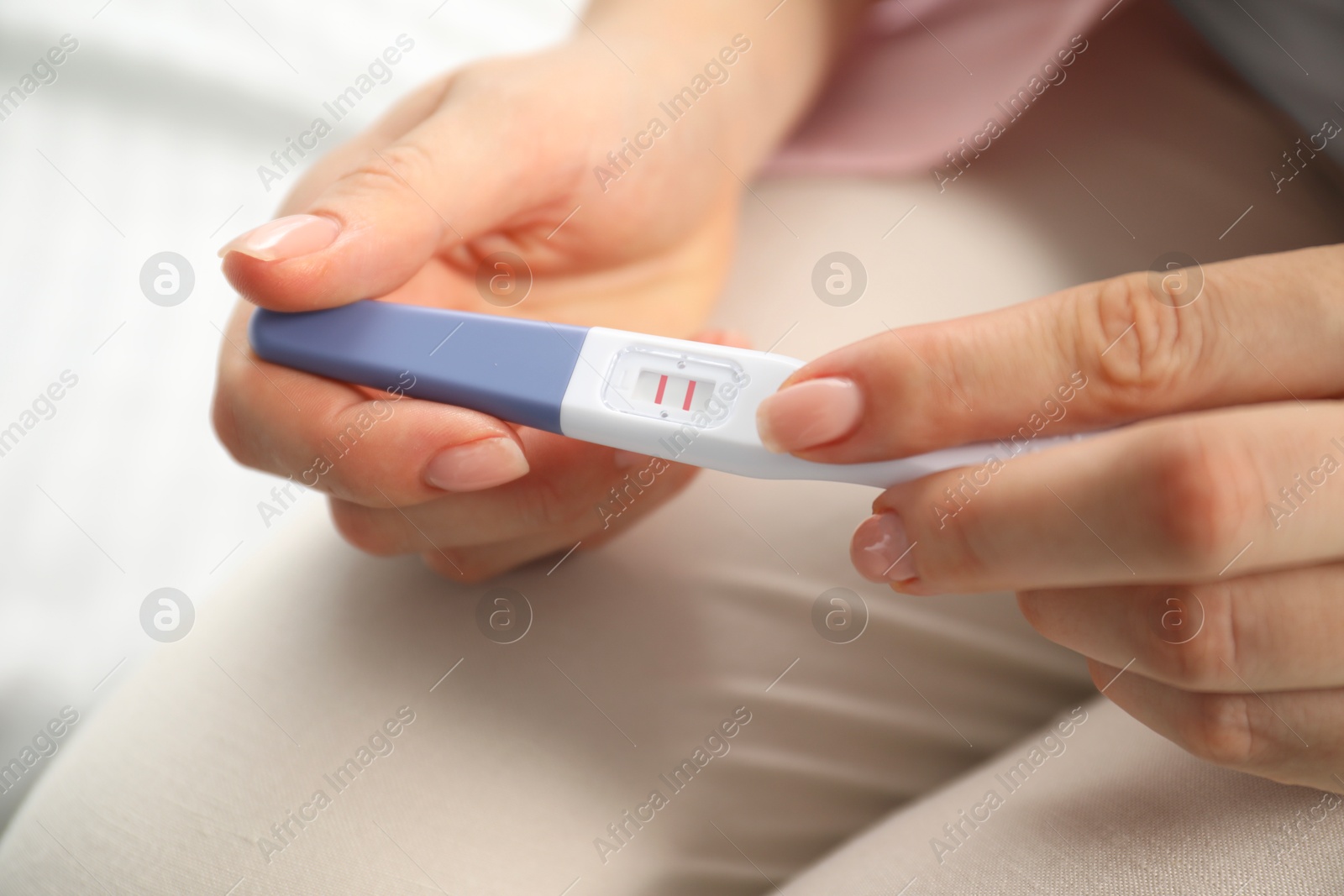 Photo of Woman holding positive pregnancy test indoors, closeup view