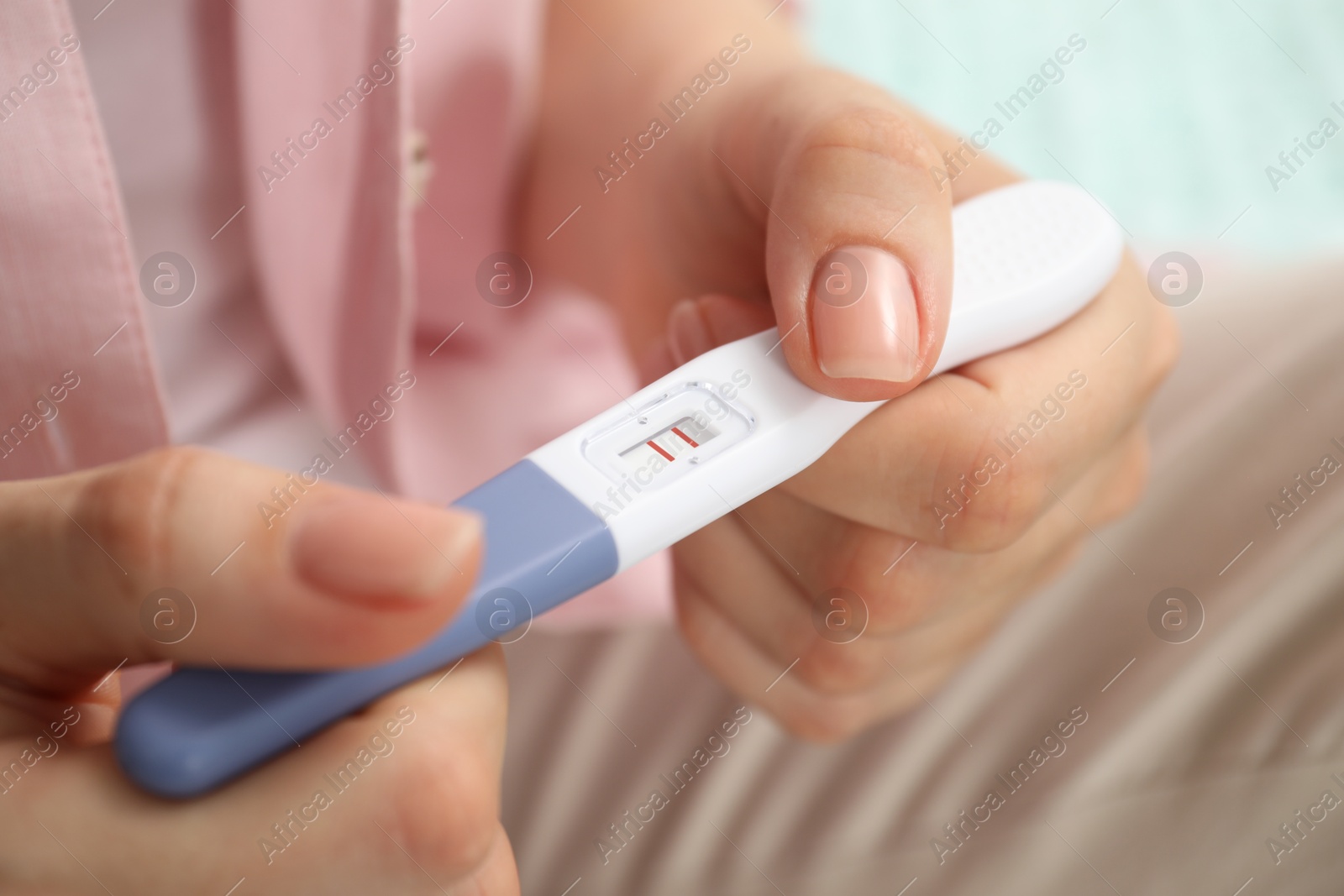 Photo of Woman holding positive pregnancy test indoors, closeup view