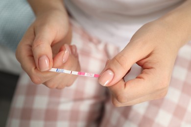 Woman holding negative pregnancy test indoors, closeup view