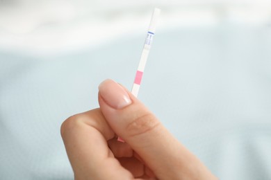 Photo of Woman holding pregnancy test indoors, closeup view