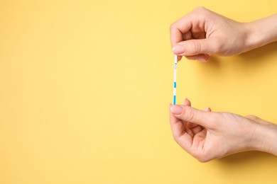 Photo of Woman holding pregnancy test on yellow background, top view. Space for text