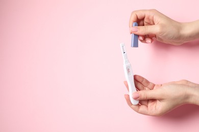 Photo of Woman holding pregnancy test on pink background, above view. Space for text