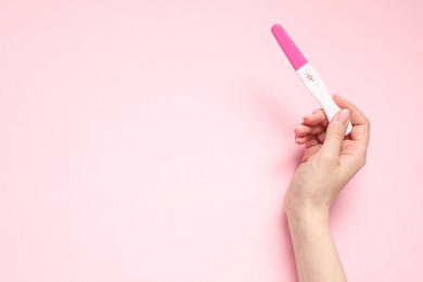 Photo of Woman holding pregnancy test on pink background, top view. Space for text