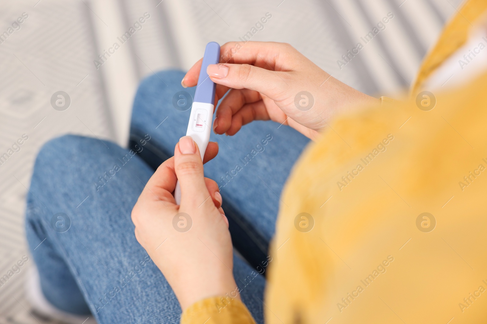 Photo of Woman holding pregnancy test in room, closeup