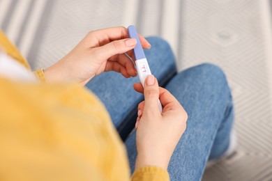 Photo of Woman holding pregnancy test in room, closeup