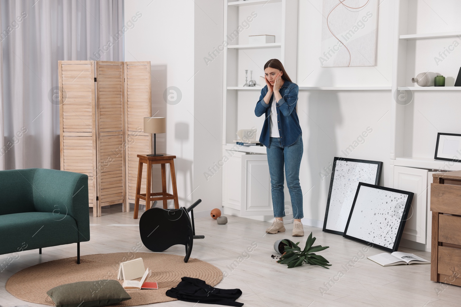 Photo of Desperate woman standing in messy living room after robbery