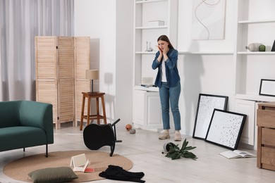 Desperate woman standing in messy living room after robbery