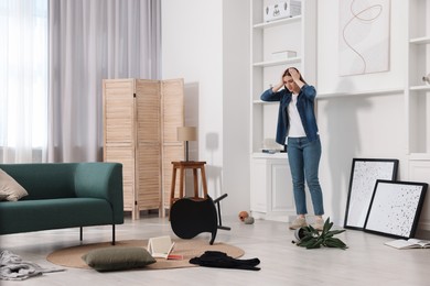 Desperate woman standing in messy living room after robbery