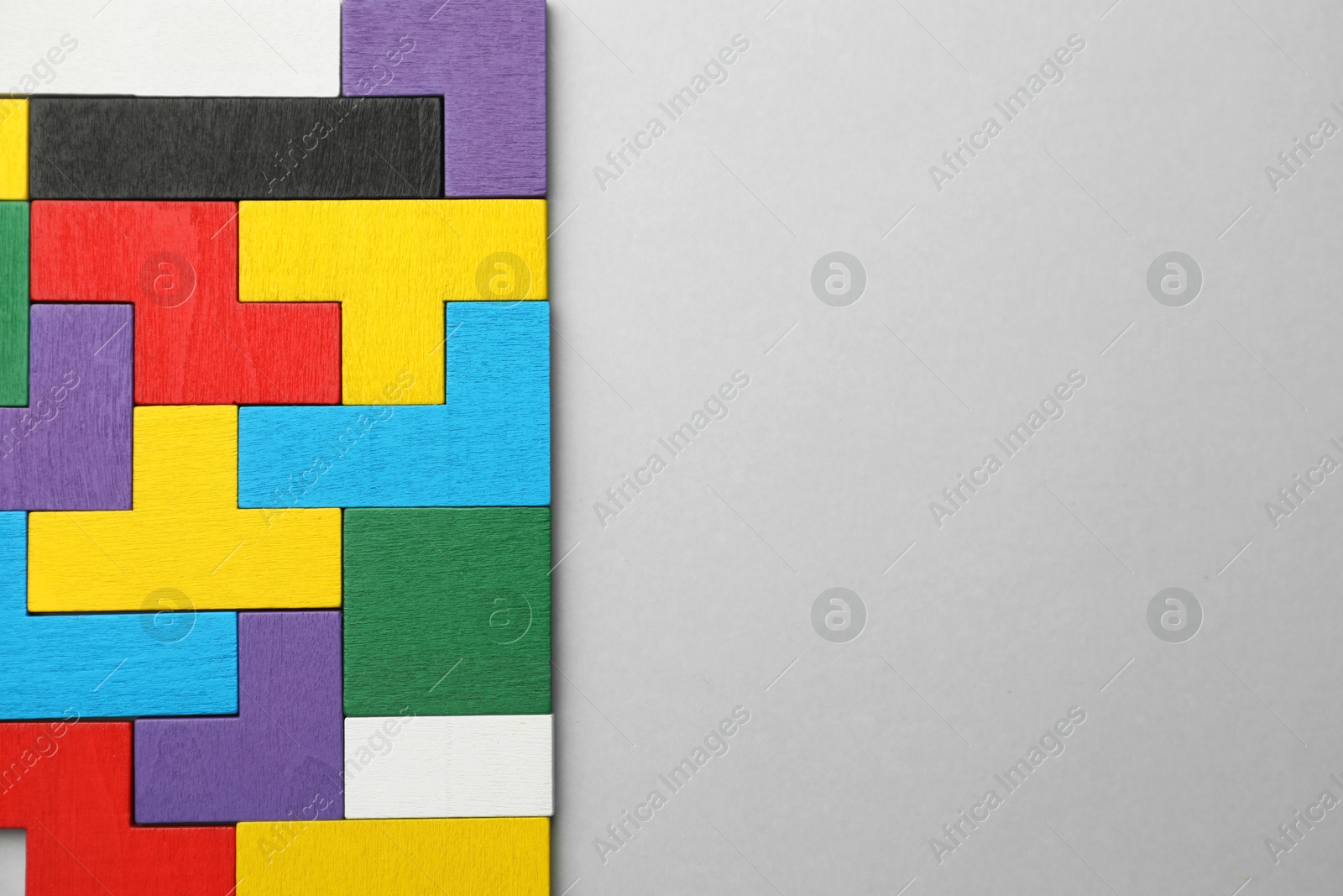 Photo of Colorful wooden puzzle pieces on light grey background, top view. Space for text