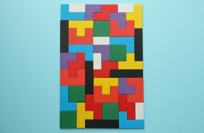 Photo of Colorful wooden puzzle pieces on light blue background, top view