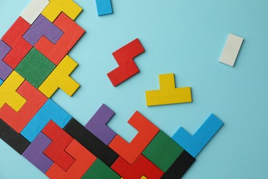 Colorful wooden puzzle pieces on light blue background, top view