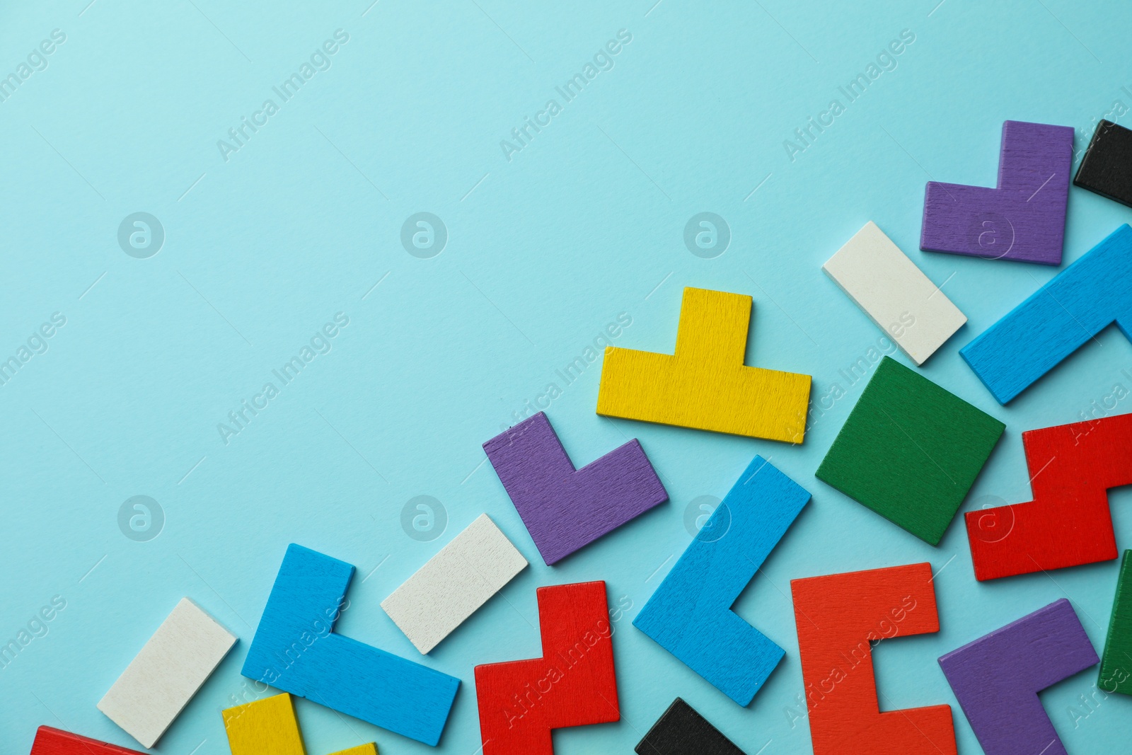 Photo of Colorful wooden puzzle pieces on light blue background, top view. Space for text