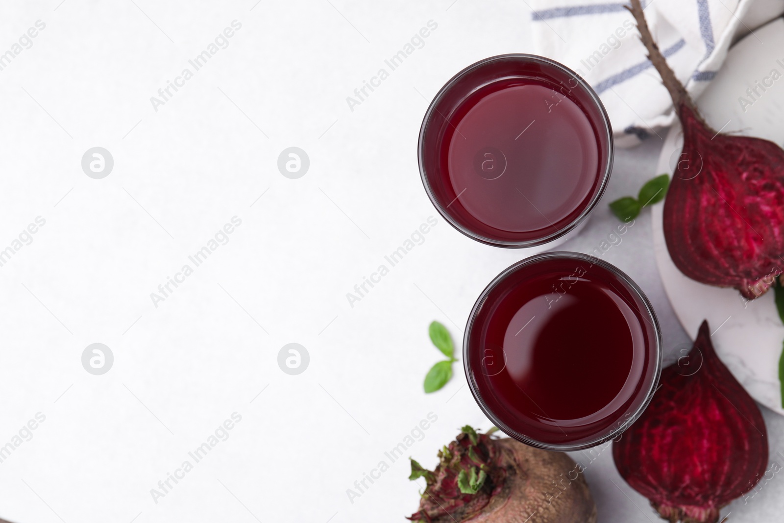 Photo of Fresh beet juice in glass and ripe vegetables on white table, flat lay. Space for text