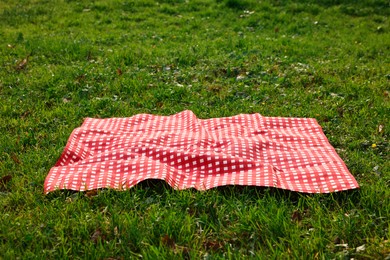 Photo of One checkered picnic tablecloth on green grass