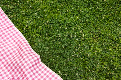 Photo of Checkered picnic tablecloth on green grass. Space for text