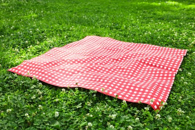 Photo of One checkered picnic tablecloth on green grass