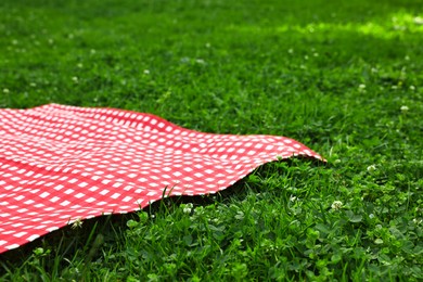 Photo of Checkered picnic tablecloth on green grass, closeup