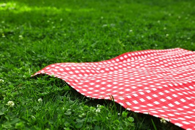 Photo of Checkered picnic tablecloth on green grass, closeup