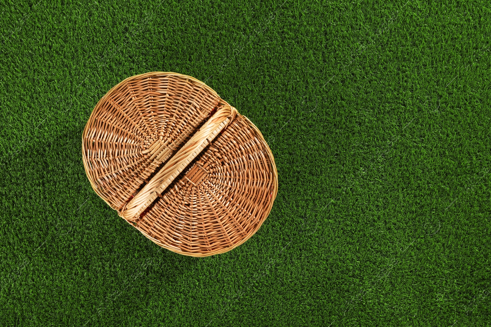 Photo of One picnic wicker basket on green grass, top view. Space for text