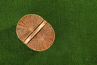 Photo of One picnic wicker basket on green grass, top view. Space for text